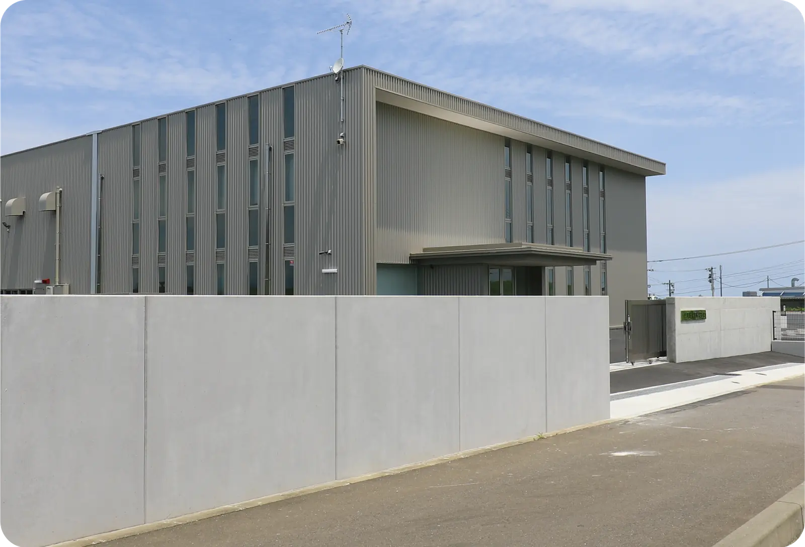 シンプルな外観の工場を囲む塀のねっこ