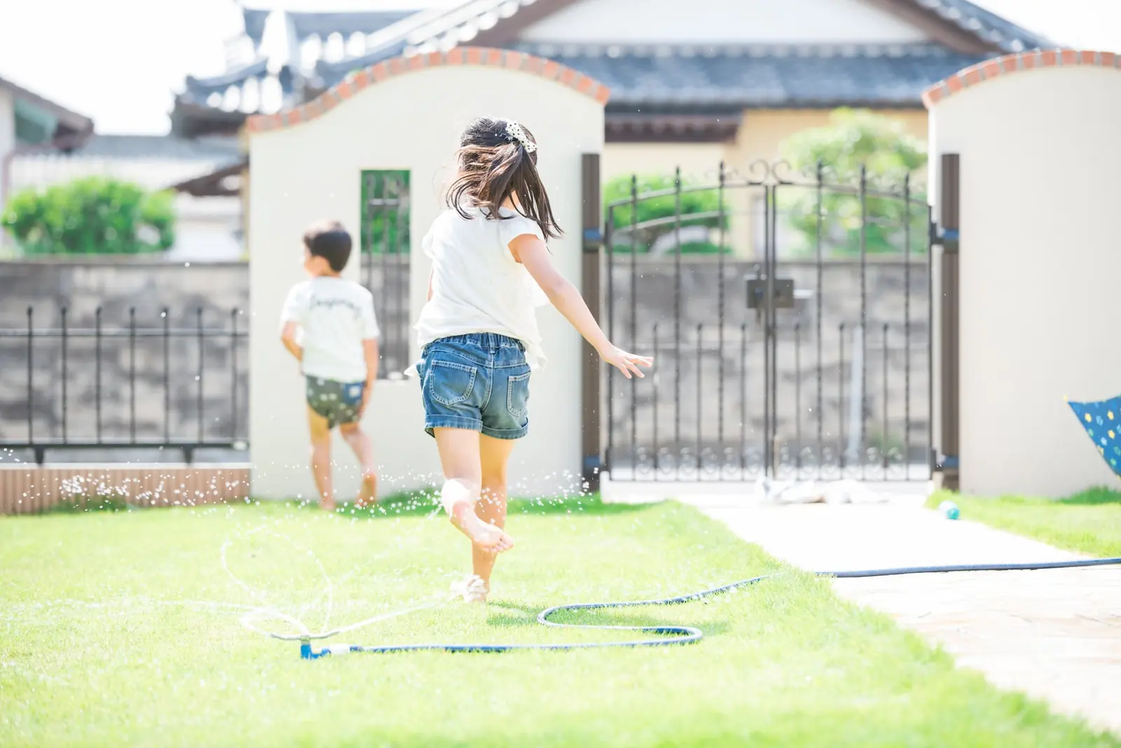 塀に囲まれた庭で水遊びする子どもたち