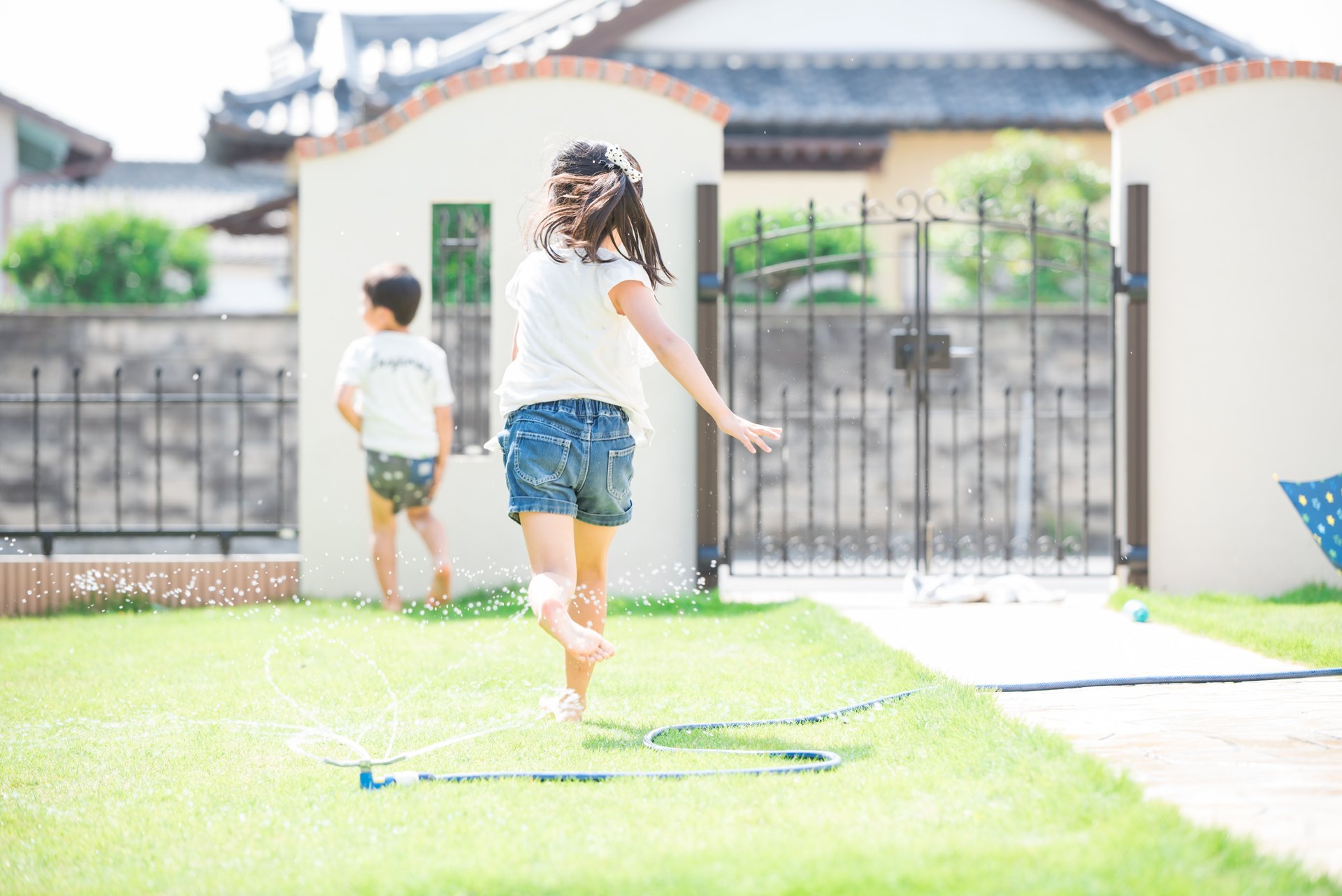 塀に囲まれた庭で水遊びする子どもたち